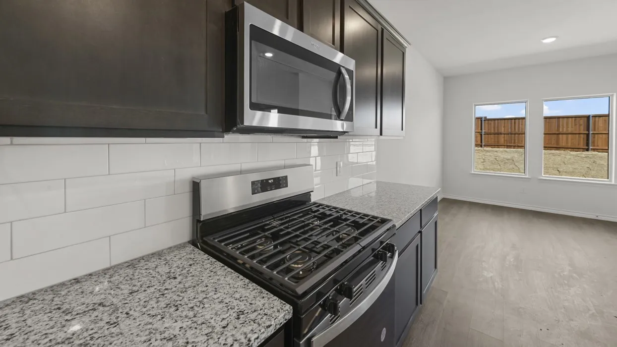 Kitchen featuring stainless steel appliances, granite-style countertops, dark wood-finish cabinetry, and a subway tile backsplash