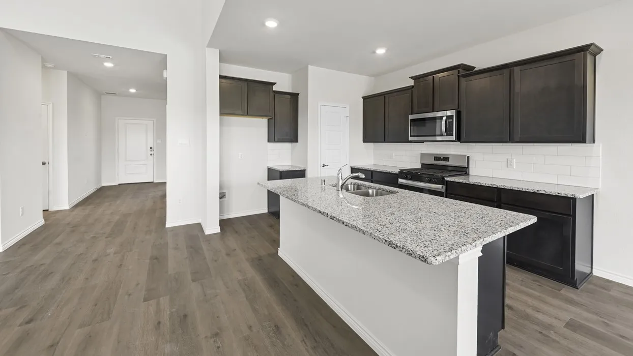 Kitchen featuring a granite island, dark wood-finish cabinetry, stainless steel appliances, a subway tile backsplash, and wood-finish flooring
