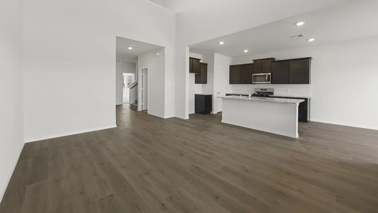 Open-concept living space featuring wood-finish flooring, a kitchen island with stone countertop, dark cabinetry, stainless steel appliances, and recessed lighting