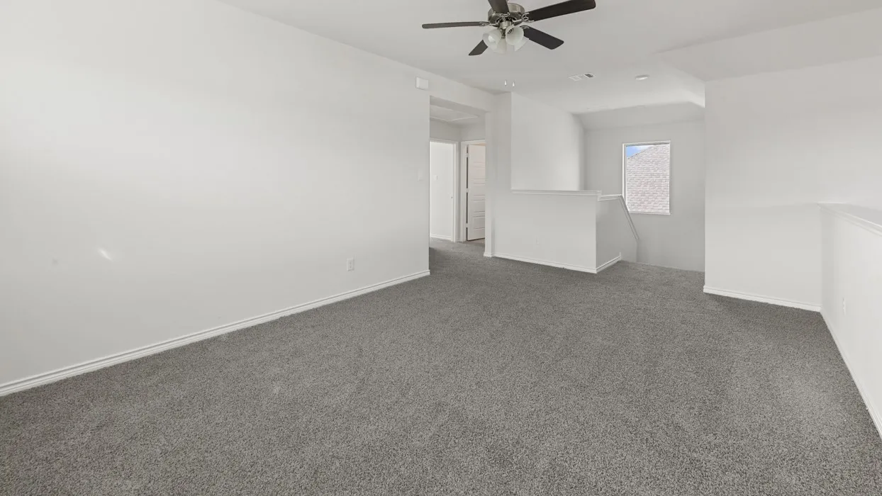 Spacious interior featuring neutral wall finishes, gray carpeting throughout, and a ceiling fan