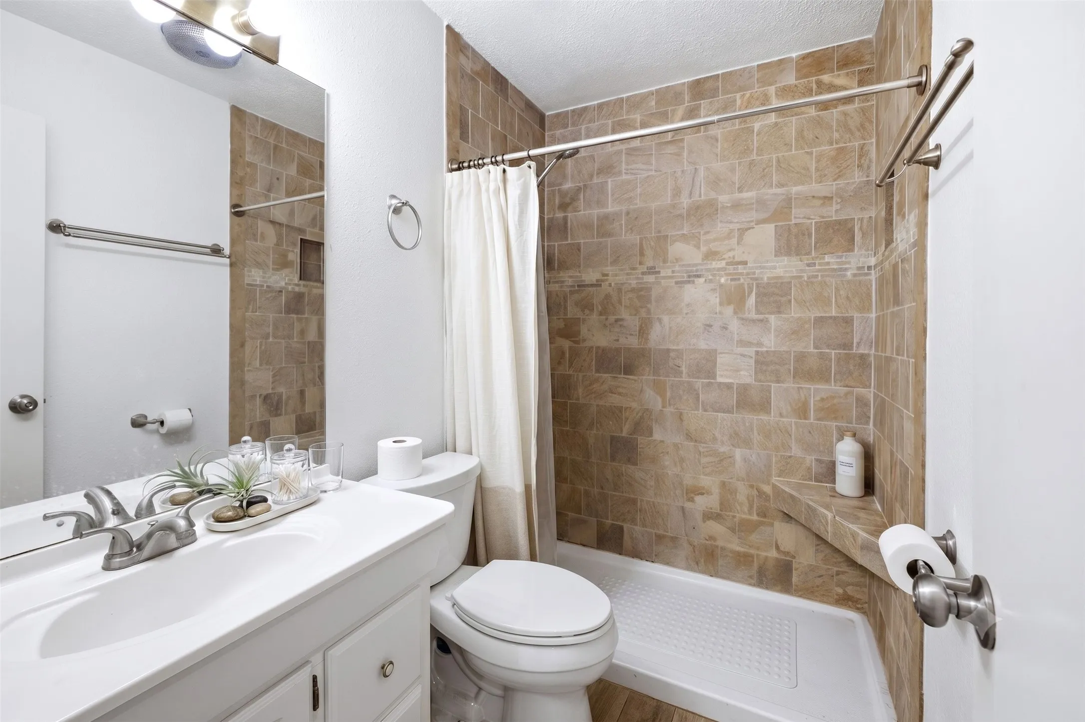 Bathroom featuring a white vanity with dual sinks, mirrored medicine cabinets, and tiled shower/tub area.