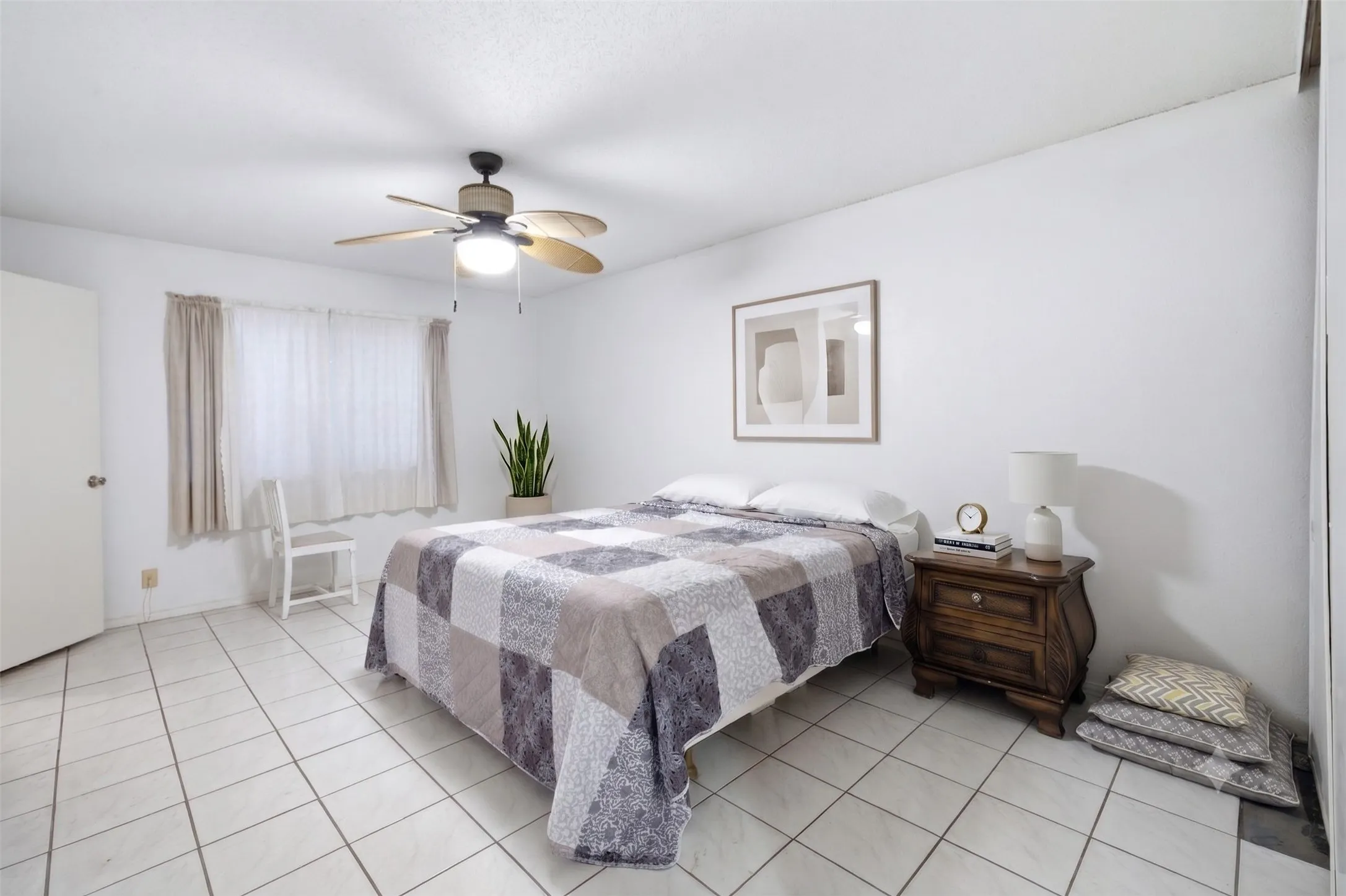 Primary bedroom featuring tiled flooring, a ceiling fan, neutral walls, framed wall art, and a bed set.