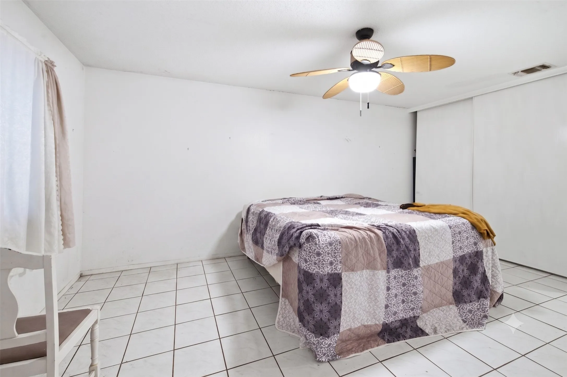 Guest bedroom with light tile floors, white walls, a ceiling fan, and a queen bed.