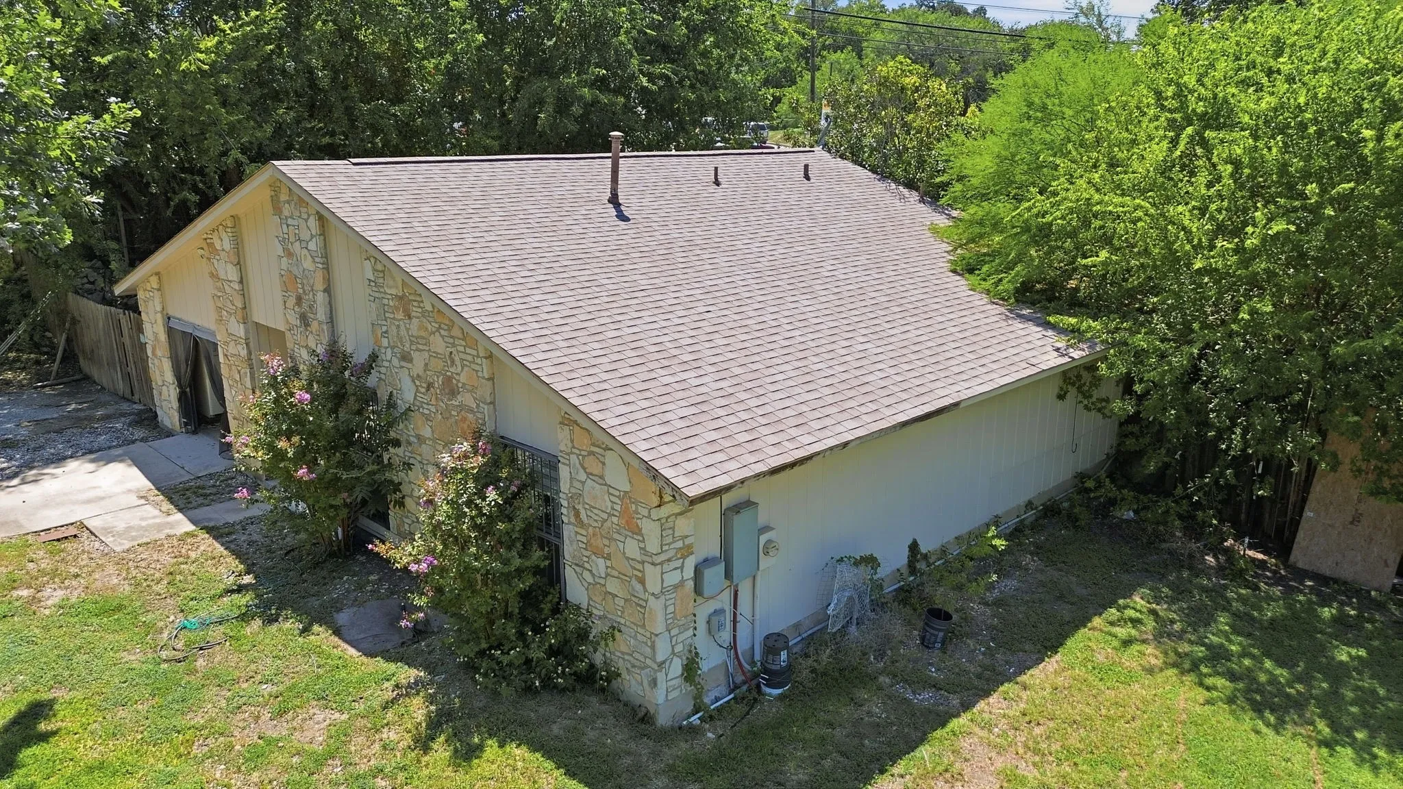 Alternate aerial view of the stone house, roof structure, and lush green landscaping.