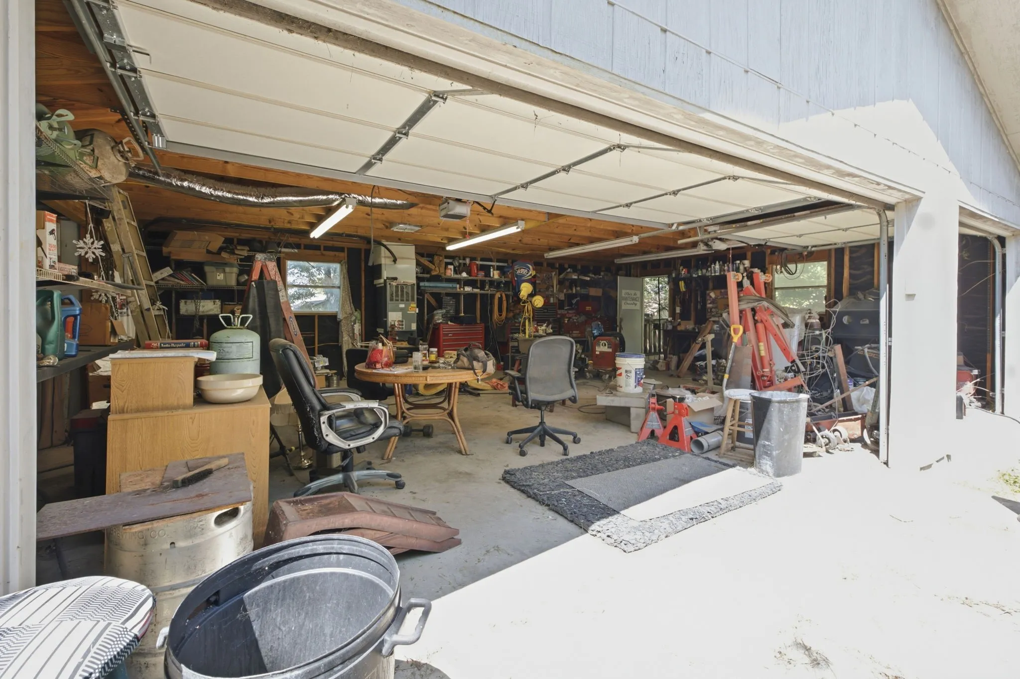 Interior view of the spacious workshop/garage featuring open garage doors, concrete floor, and storage space.