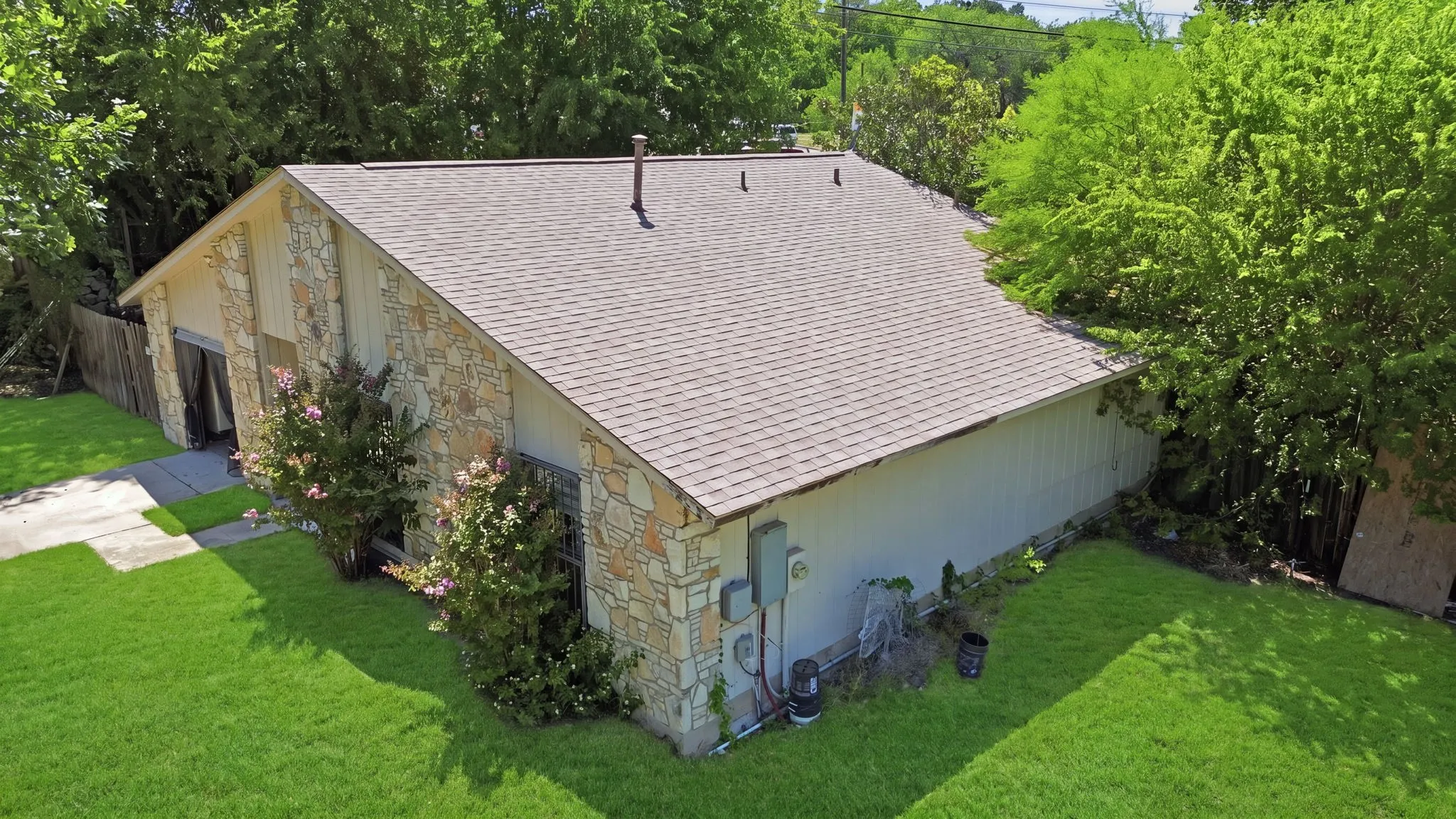 Aerial perspective of the residential structure showcasing the expansive roof and leafy backyard trees.