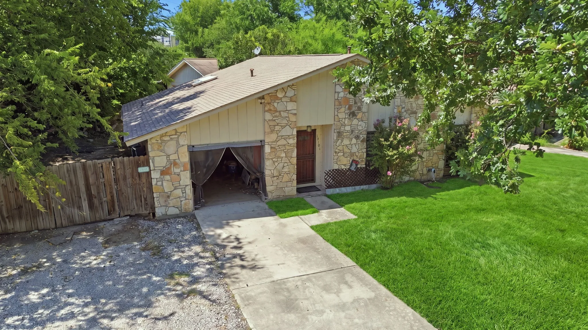 High-angle view of the front exterior, wide concrete driveway, double garage, and manicured lawn.