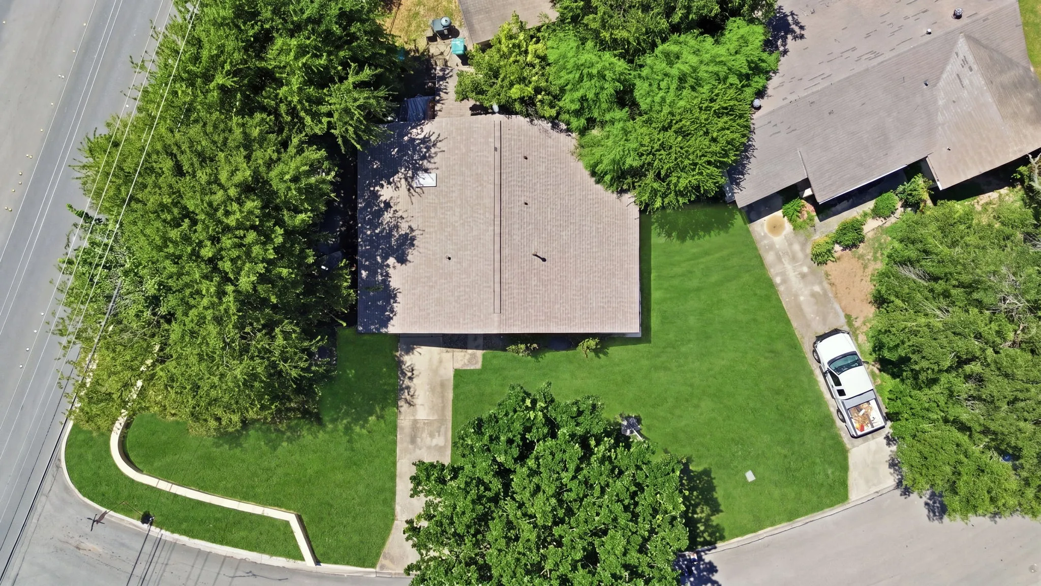 Overhead aerial shot showing the property lot boundaries, roof structure, front lawn, and street view.