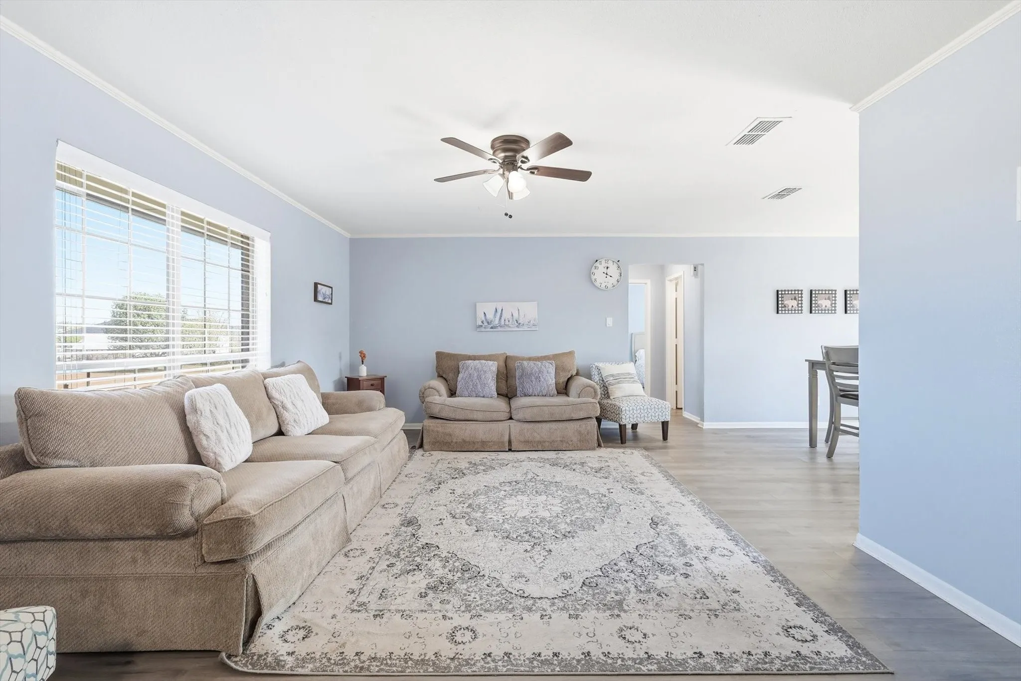 Living room featuring crown molding, wood finished floors, and ceiling fan
