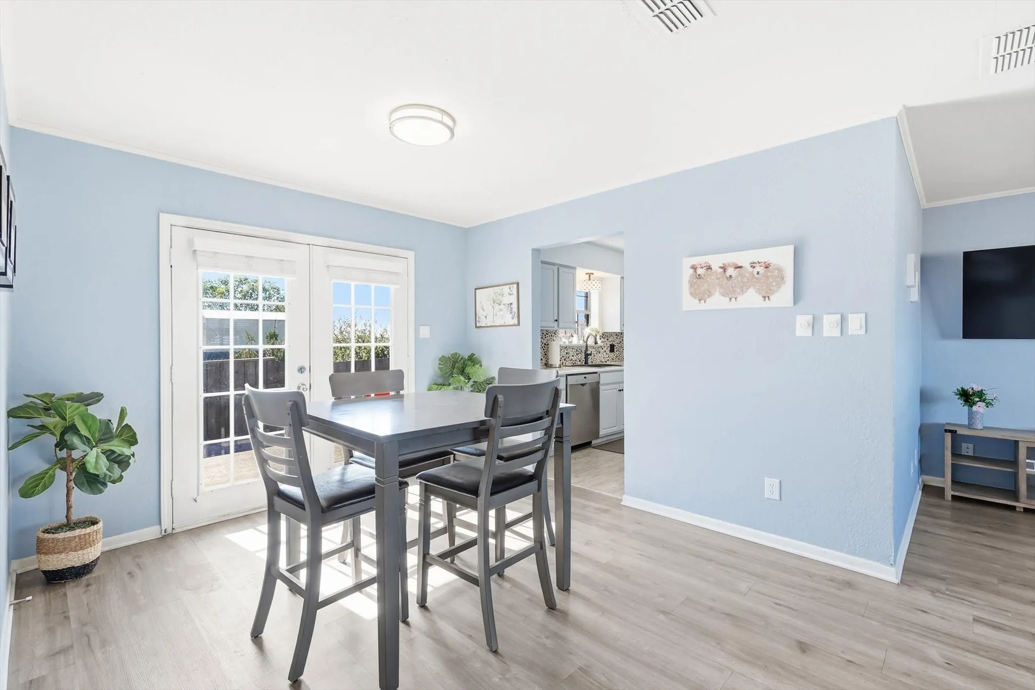 Dining room featuring french doors, light wood-style floors, and ornamental molding