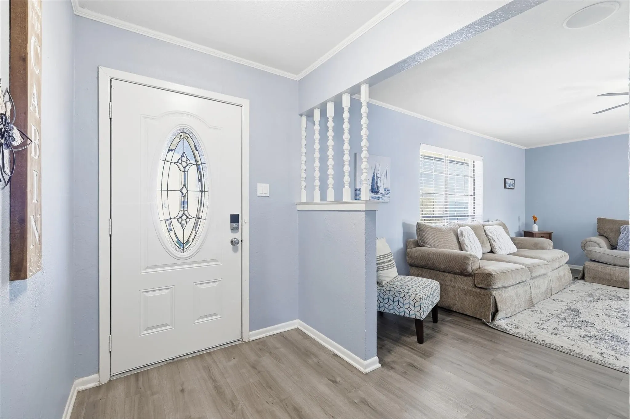 Entrance foyer with crown molding, light wood-type flooring, and ceiling fan