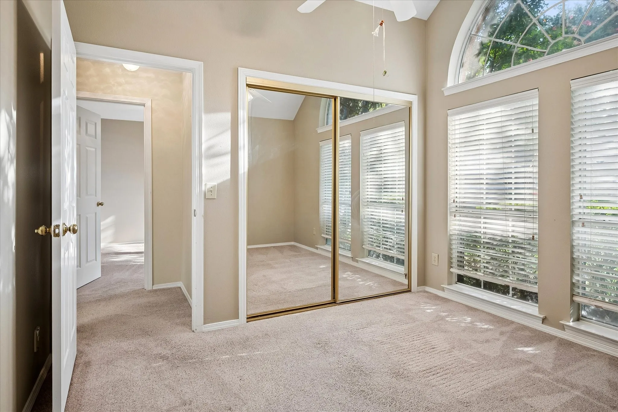 Third bedroom also with front-facing windows and mirrored closet doors. This view shows the shared bay entry to second bedroom.