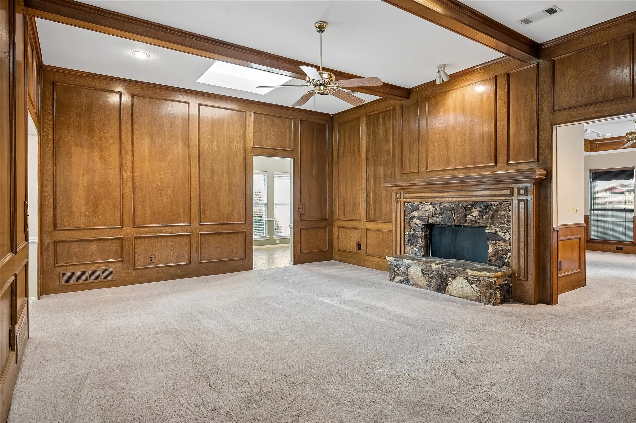 Primary living room with decorative fireplace. This photo view shows threshold to front entry on left, threshold to kitchen at center, and threshold to secondary living room on right.