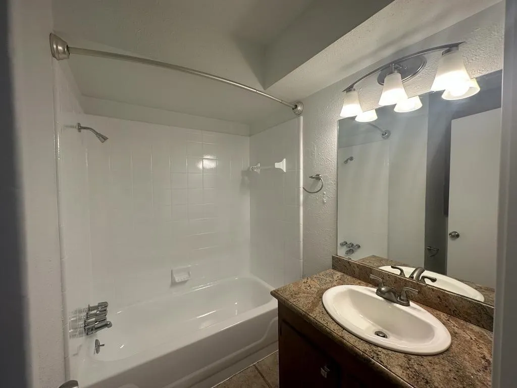 Modern bathroom featuring a frameless glass-enclosed shower with chrome fixtures, an oval porcelain sink set into a granite-finish vanity countertop, and polished chrome faucet