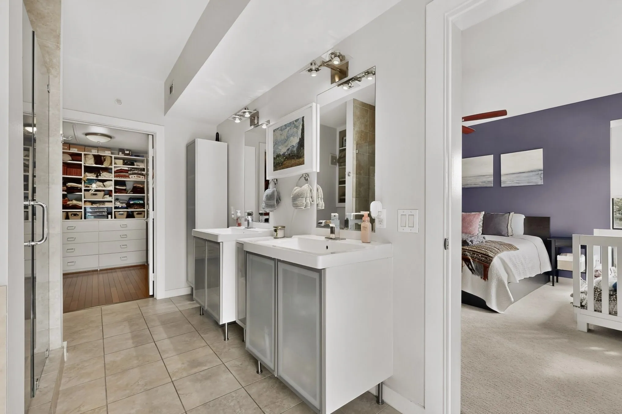 Bathroom featuring dual vanities with white countertops, integrated sinks, and under-sink cabinetry with frosted panels