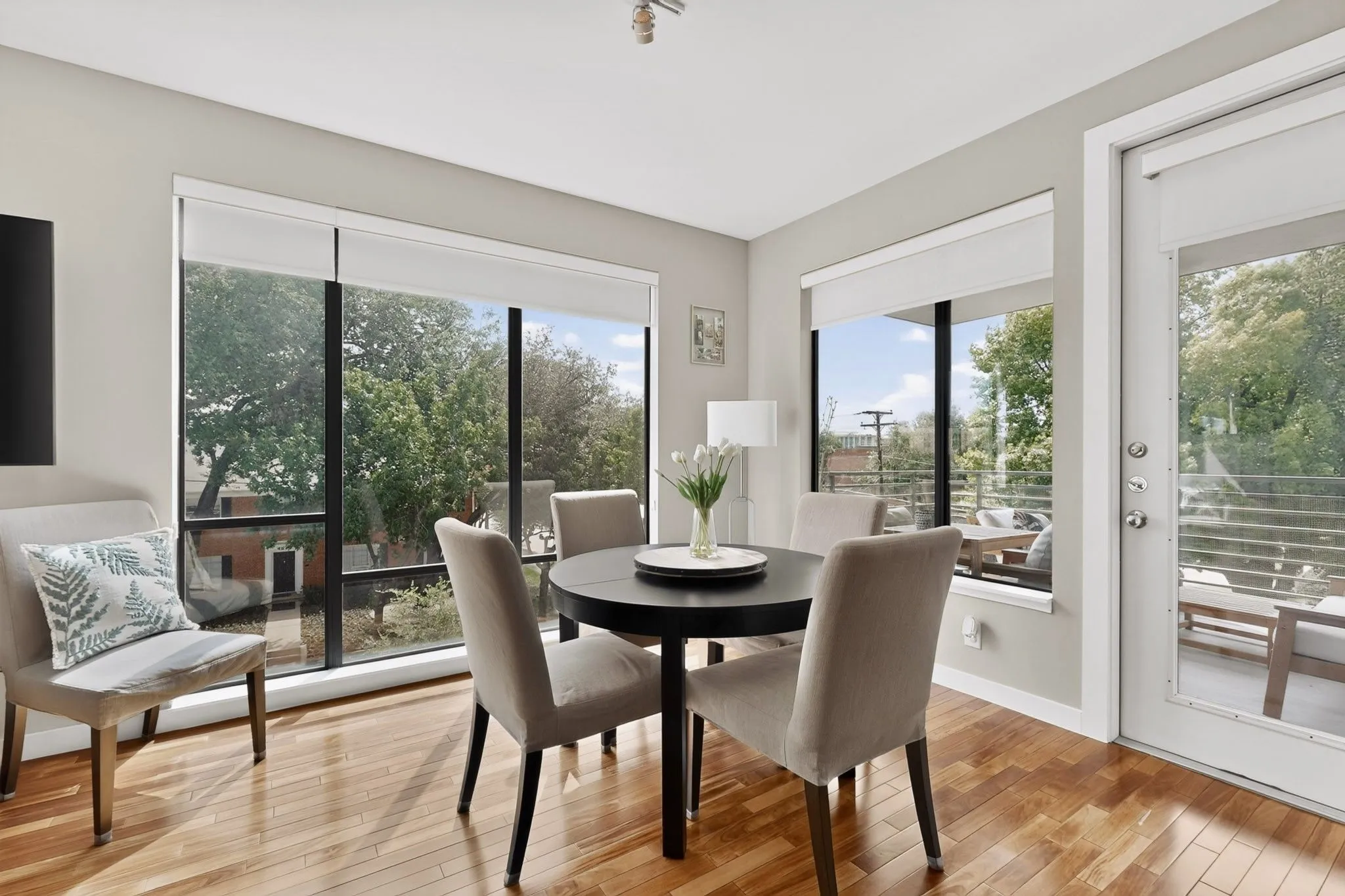 Dining area featuring hardwood flooring, expansive windows, white roller shades, a balcony access door, and recessed lighting