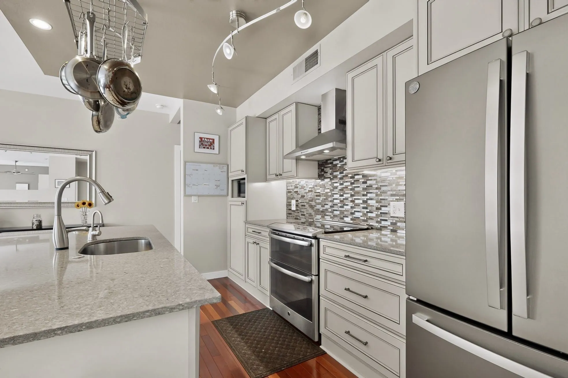 Modern kitchen featuring stainless steel appliances, light-toned cabinetry, and wood-finish flooring