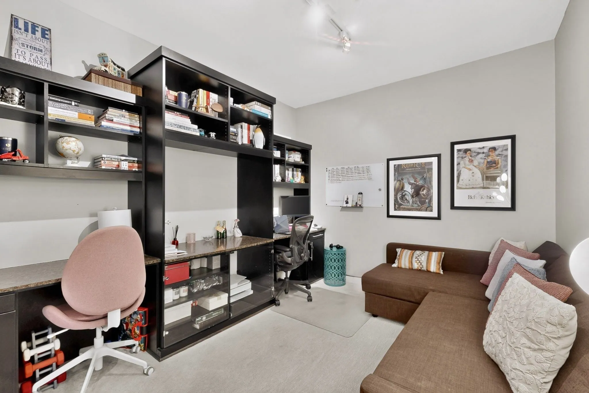 Integrated custom built-in shelving with desk space features a stone-finish countertop