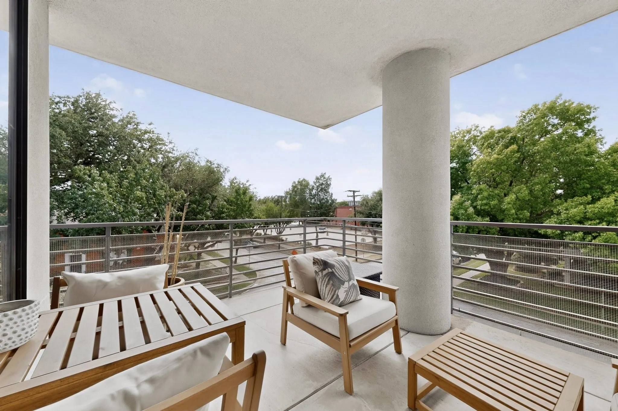Spacious outdoor balcony featuring a concrete surface, modern metal railings, and a substantial support column