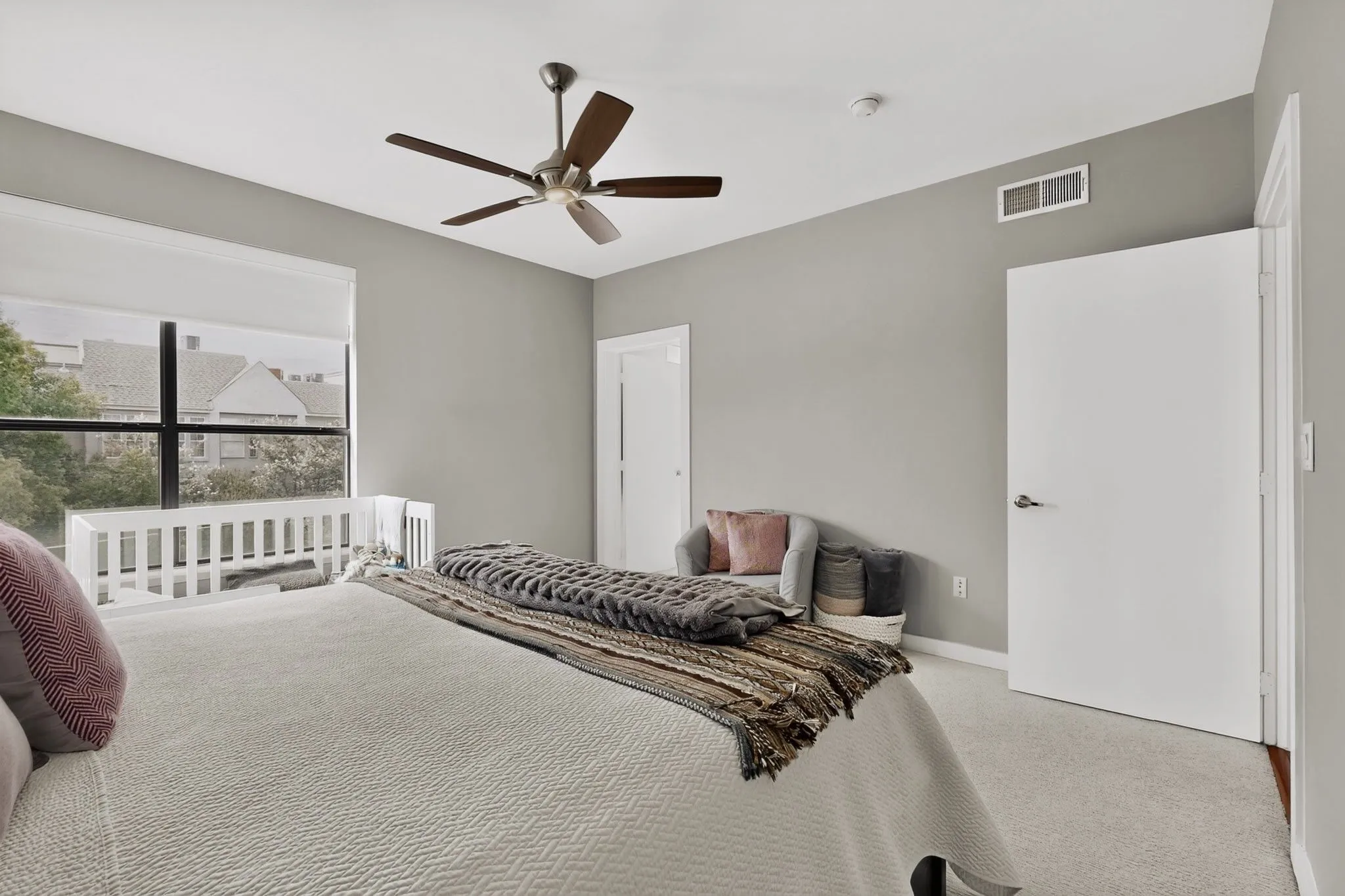 Spacious room featuring a large window, light gray walls, and carpet flooring