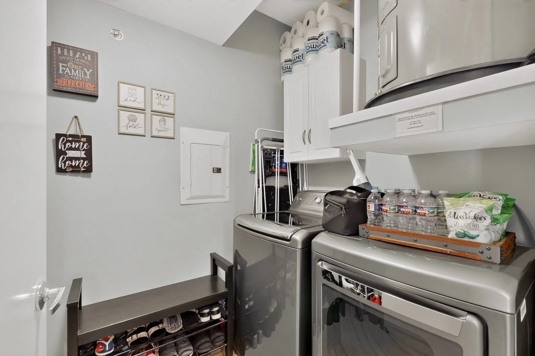 Laundry area featuring a side-by-side washer and dryer, wall-mounted electrical panel, and white upper cabinetry