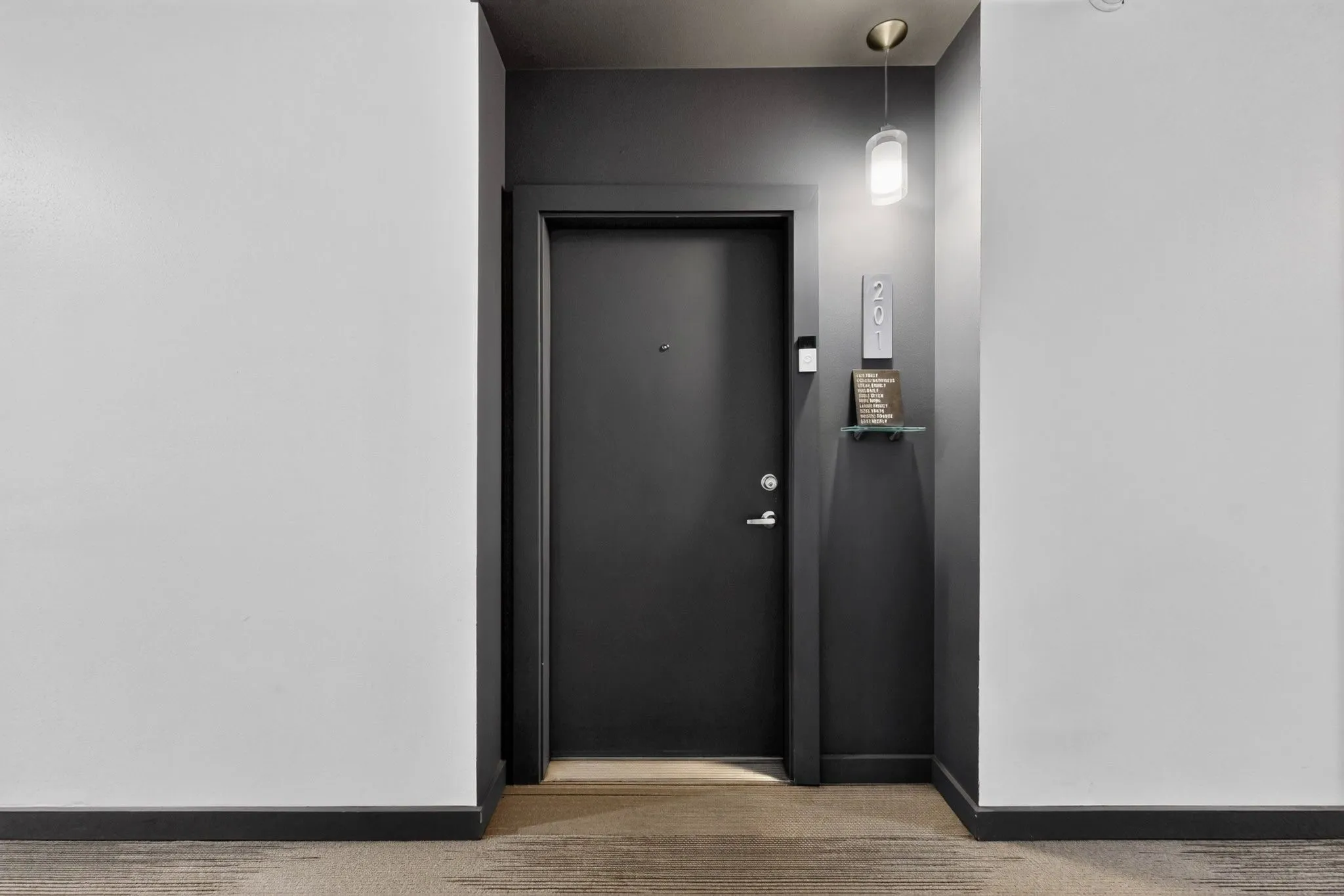Contemporary entryway featuring a dark gray door and trim, light gray walls, a modern pendant light fixture, and a glass wall shelf