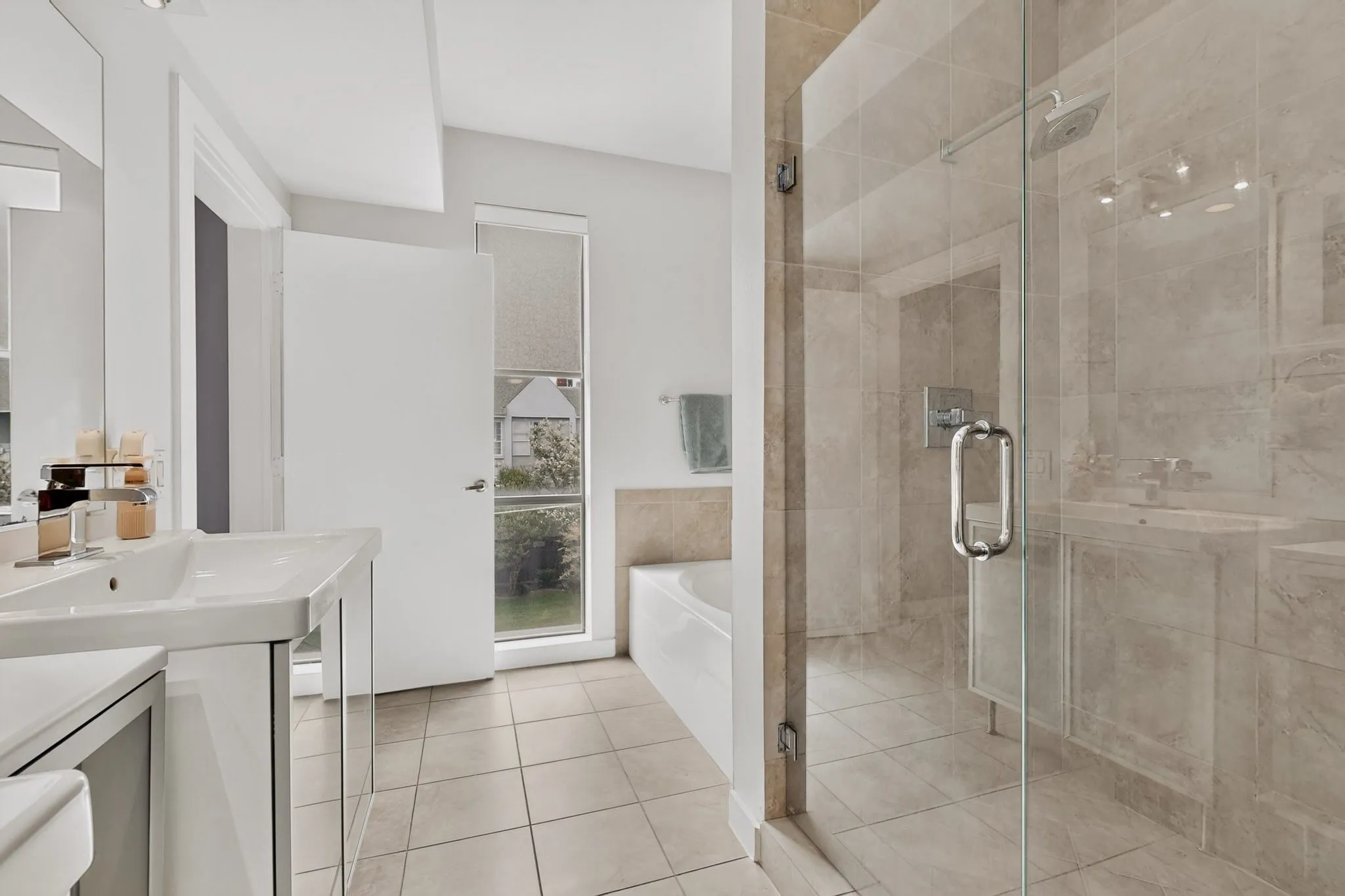 Spacious bathroom featuring a glass-enclosed shower with tile surround, a freestanding bathtub, and a large vanity with an integrated sink