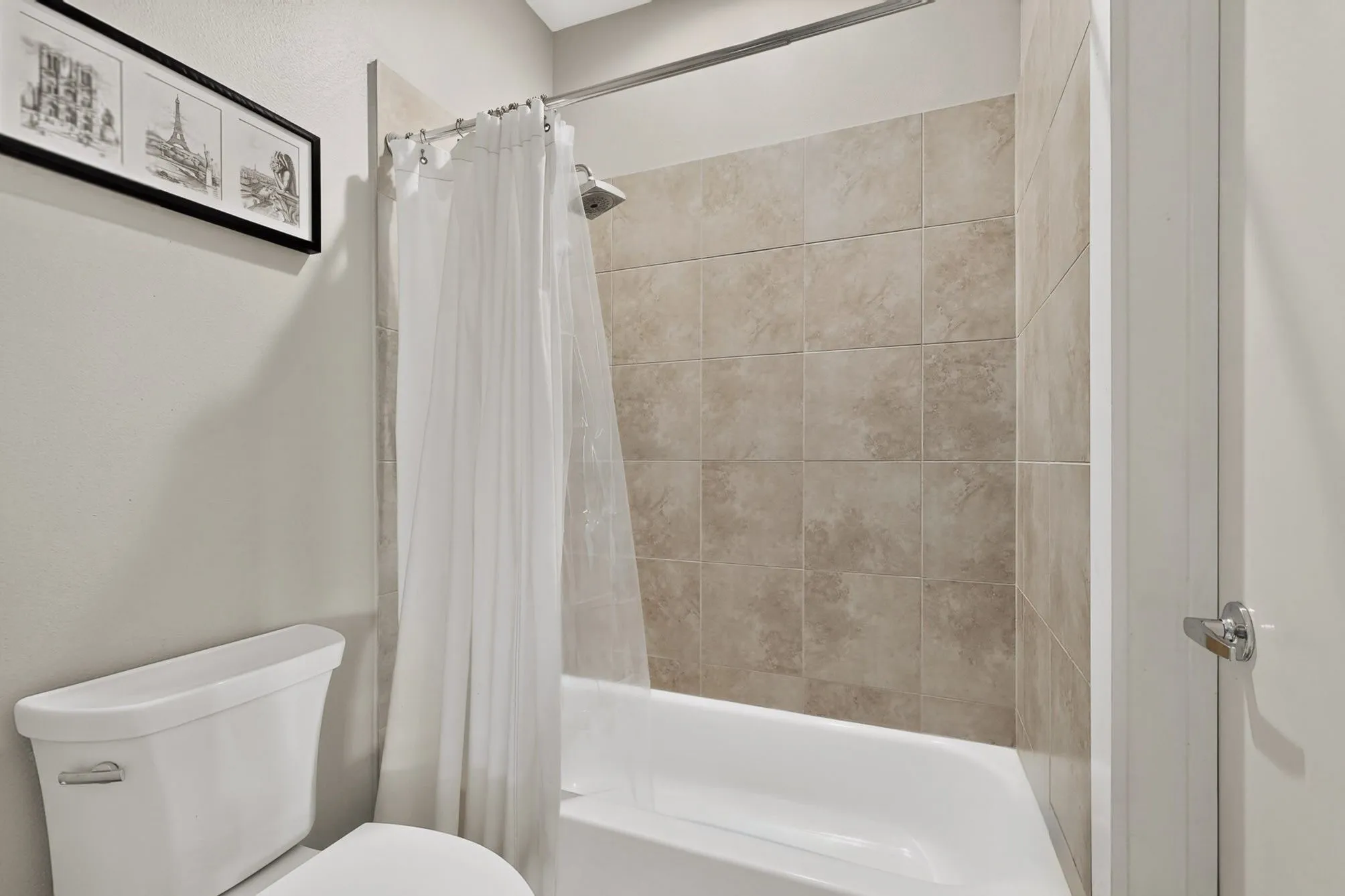 Bathtub with neutral-toned tiled surround and a chrome showerhead