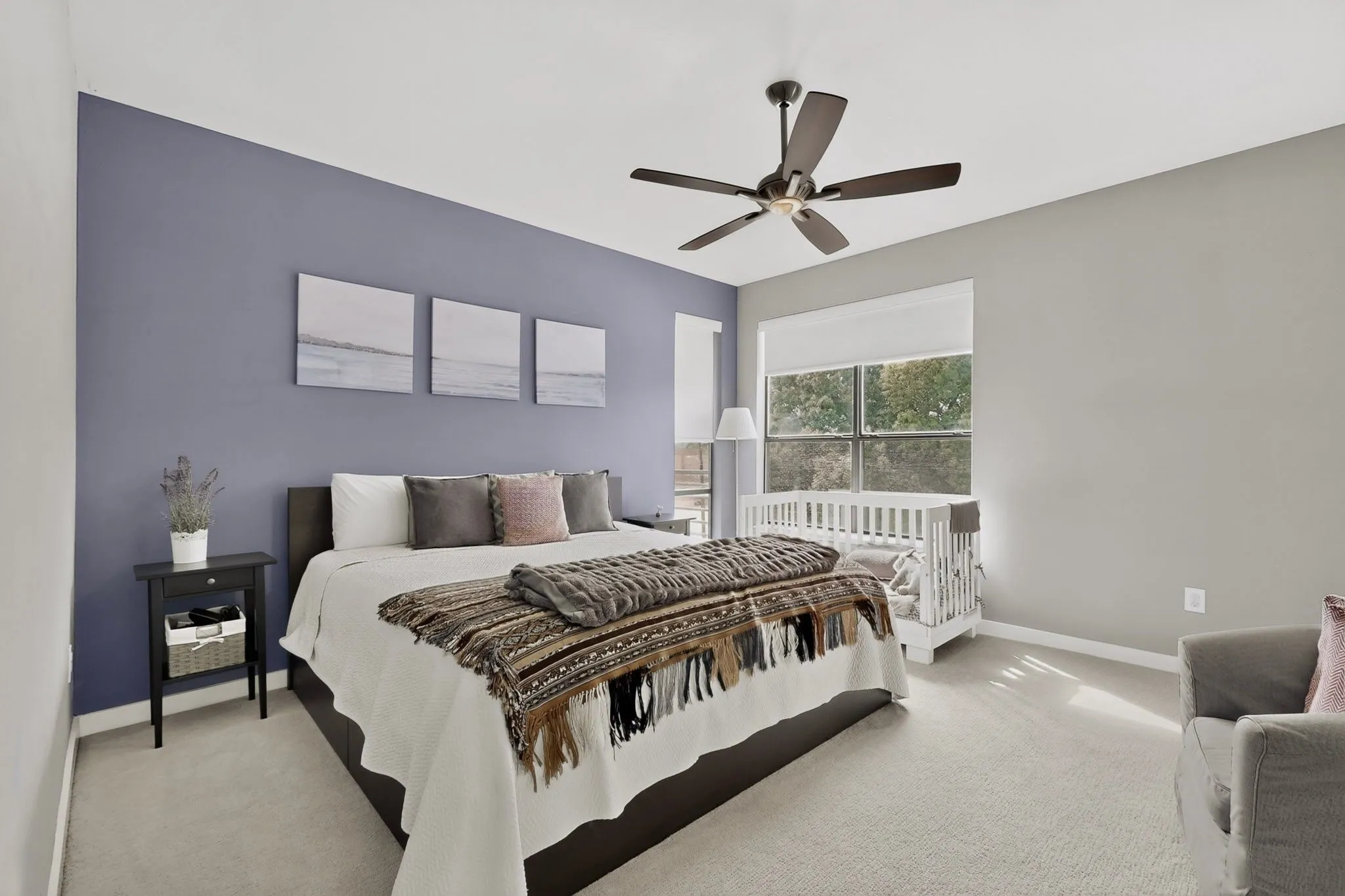 Spacious room featuring neutral carpeting, a large window with roller shades, and a ceiling fan