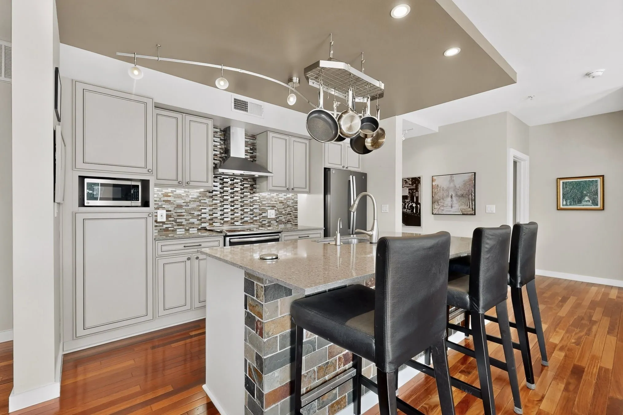 Kitchen featuring light grey cabinetry, a multi-tone tile backsplash, and a built-in microwave