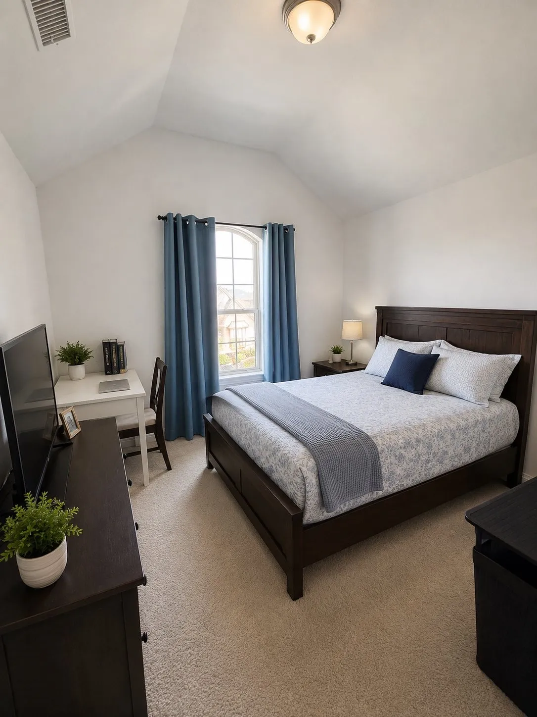Vaulted ceiling, arched window, wall-mounted light fixture, carpeted flooring, built-in desk area