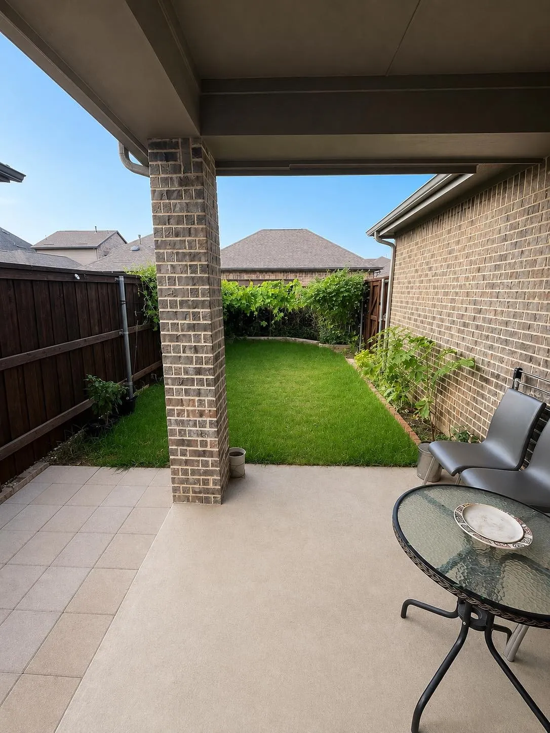 Covered patio with brick columns, concrete flooring, and a tiled section