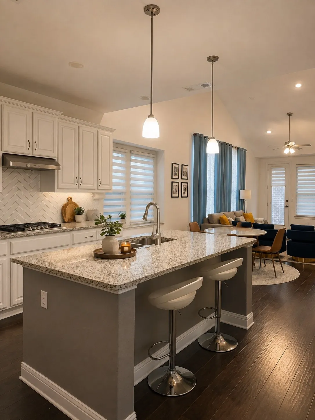 Open-concept living space featuring a kitchen island with seating, a stainless steel sink, and pendant lighting