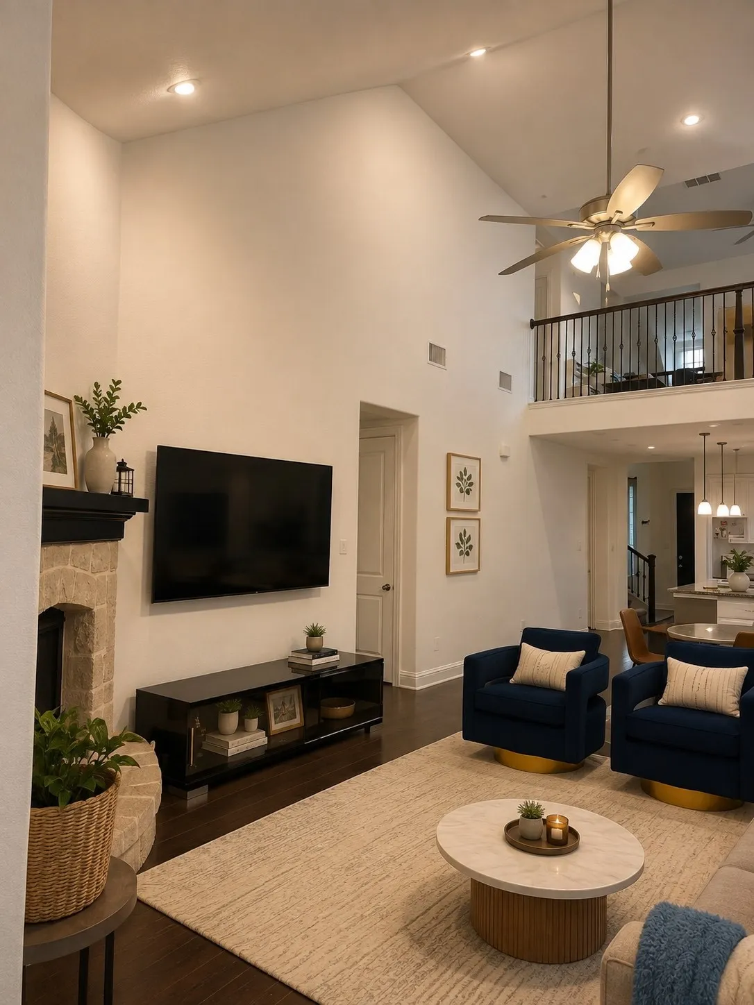 Soaring vaulted ceilings with recessed lighting, dark wood-finish flooring, stone-clad fireplace with a dark mantel, and an upper-level interior balcony with a metal railing