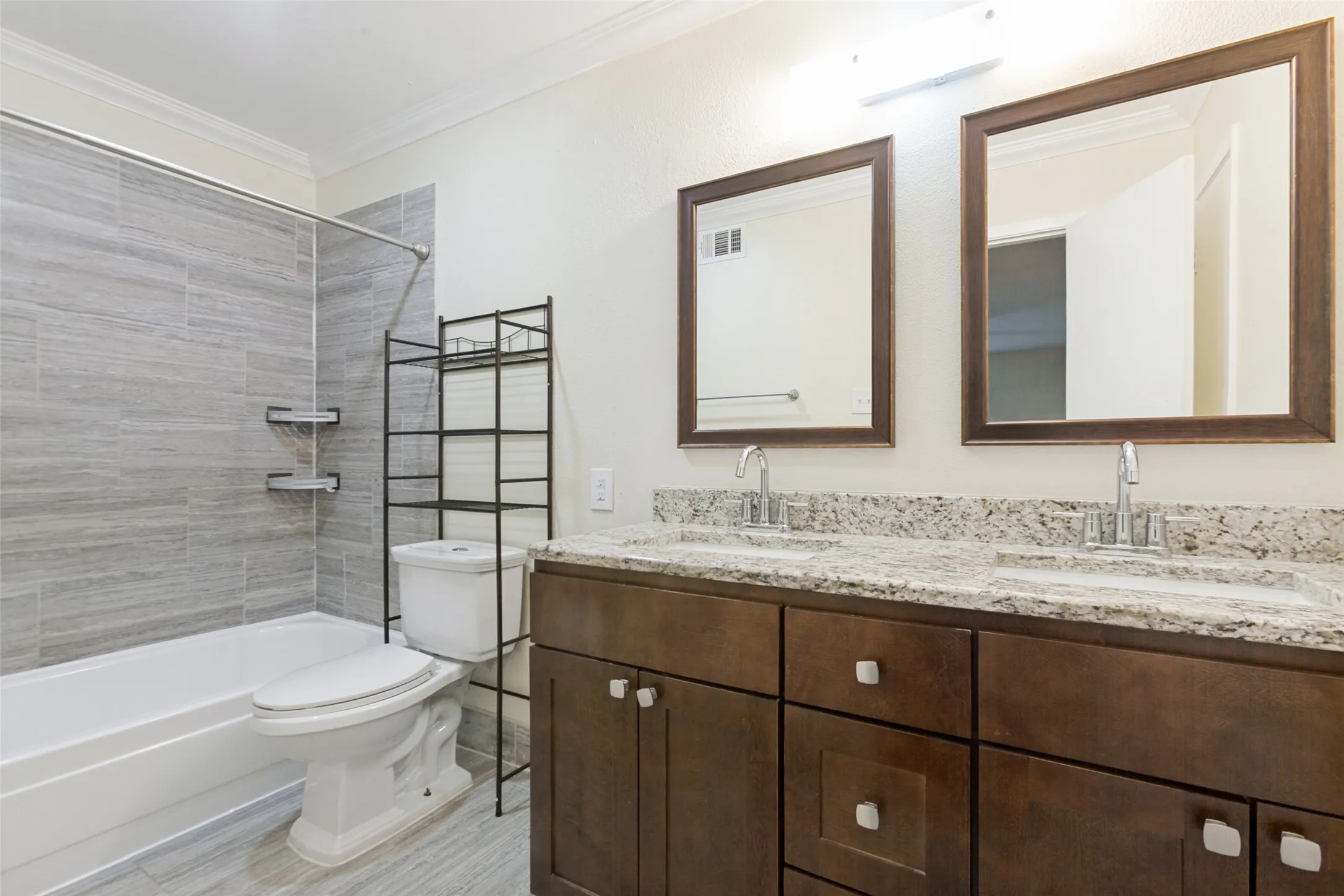 Bathroom featuring a dual vanity with a granite countertop, undermount sinks, and wood-finish cabinetry