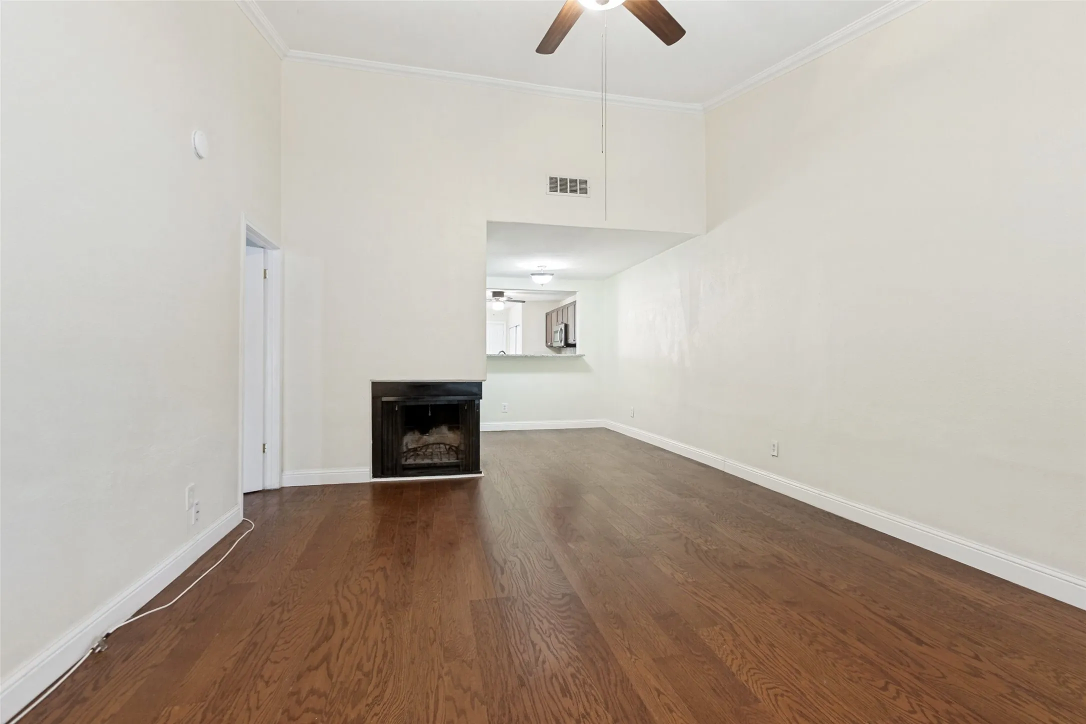 Spacious room featuring wood-finish flooring, a contemporary fireplace, and a ceiling fan