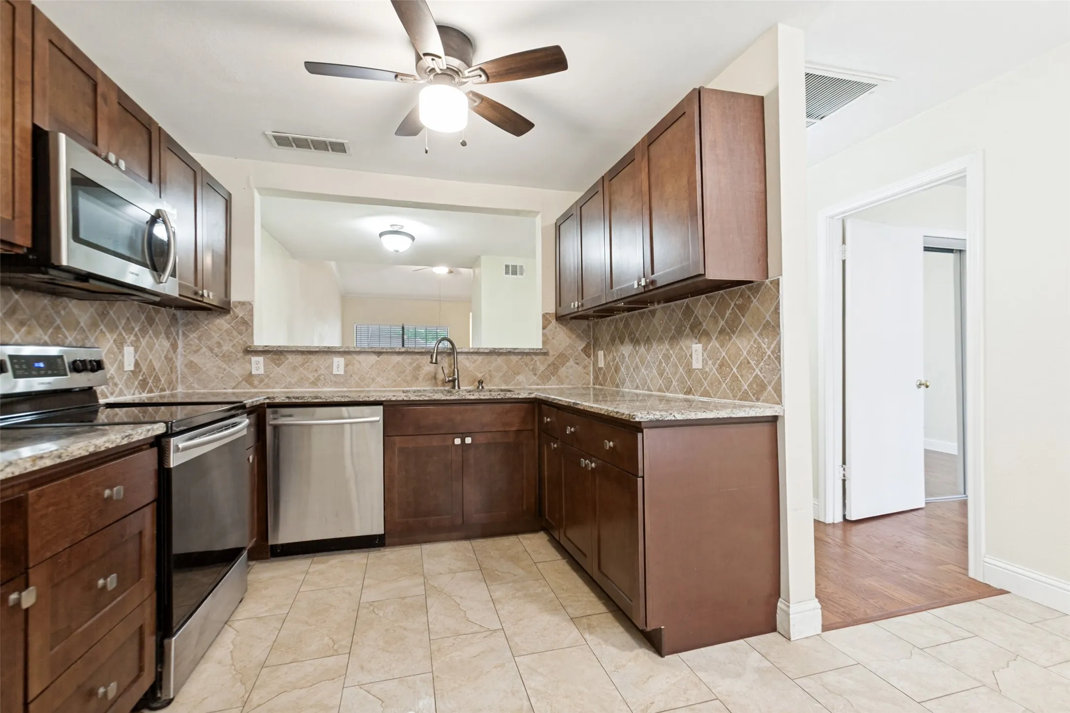 Kitchen featuring wood cabinetry, granite countertops, tile flooring, and stainless steel appliances