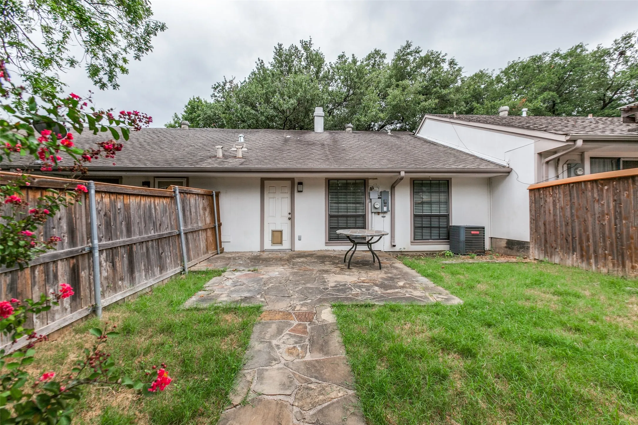 Private backyard featuring a flagstone patio, manicured lawn, and perimeter wood fencing