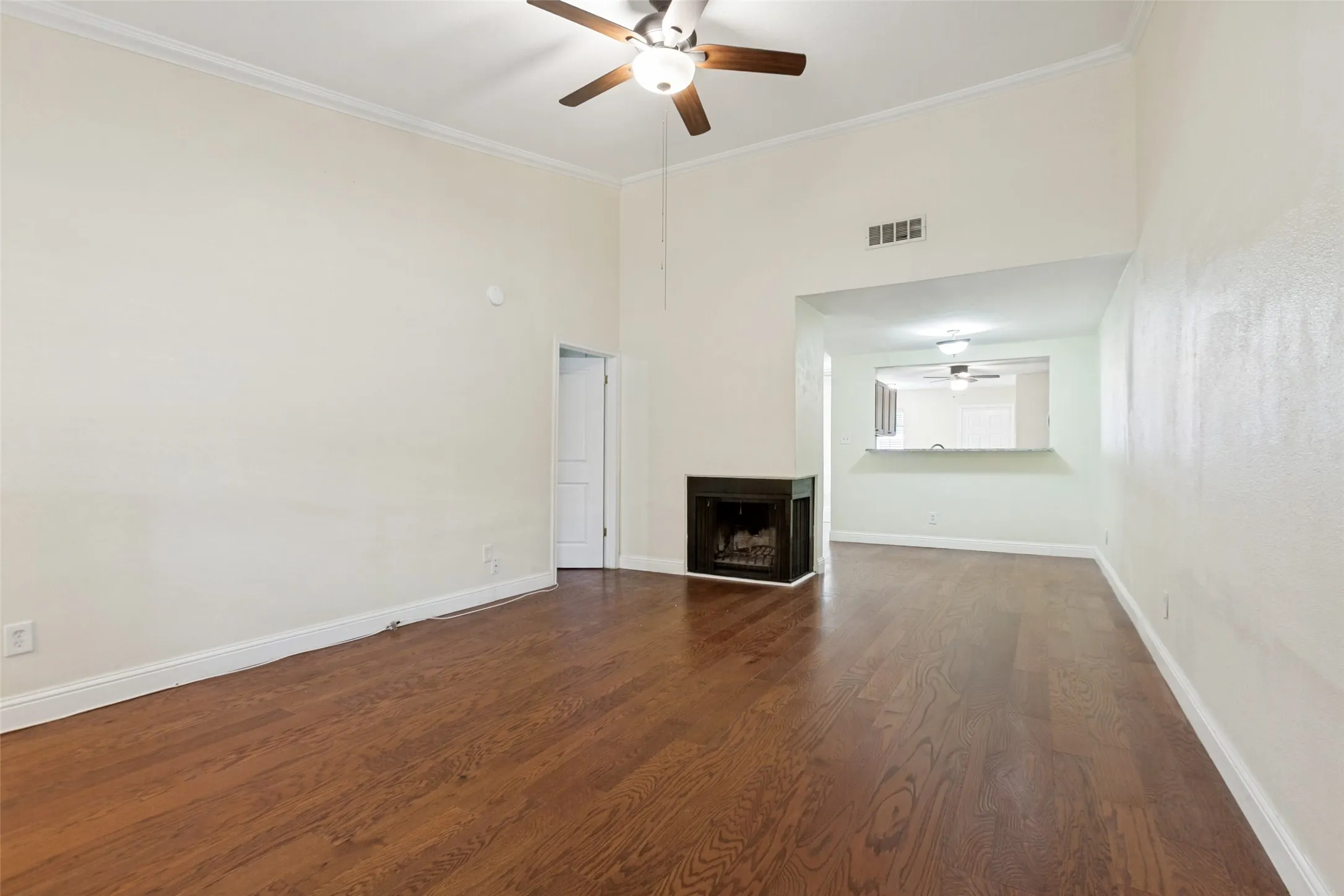 Spacious living area featuring wood-finish flooring, a corner fireplace, and a vaulted ceiling