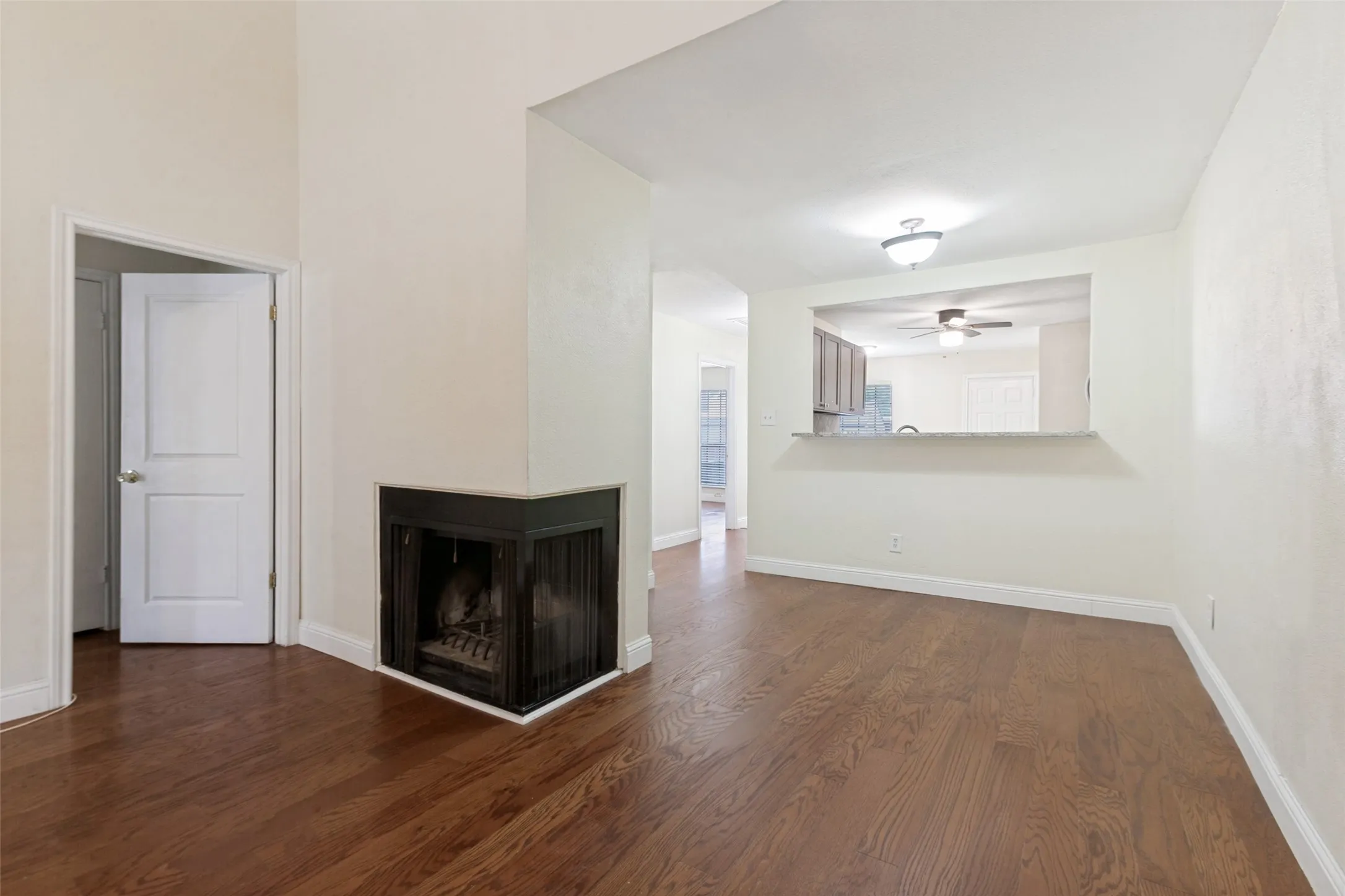 Living area featuring wood-finish flooring, a corner fireplace, and a pass-through window with a breakfast bar