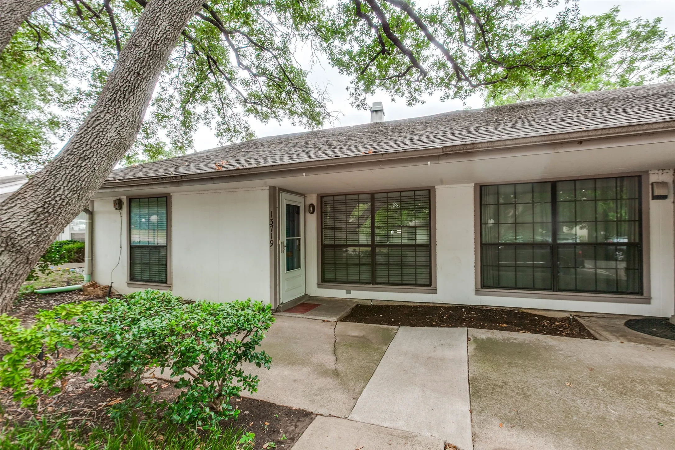 White exterior with multiple large windows featuring horizontal blinds