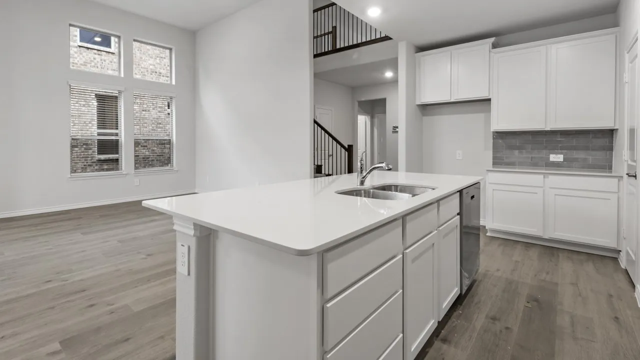 Kitchen island featuring a dual-basin stainless steel sink, white shaker cabinetry, and light-toned countertops