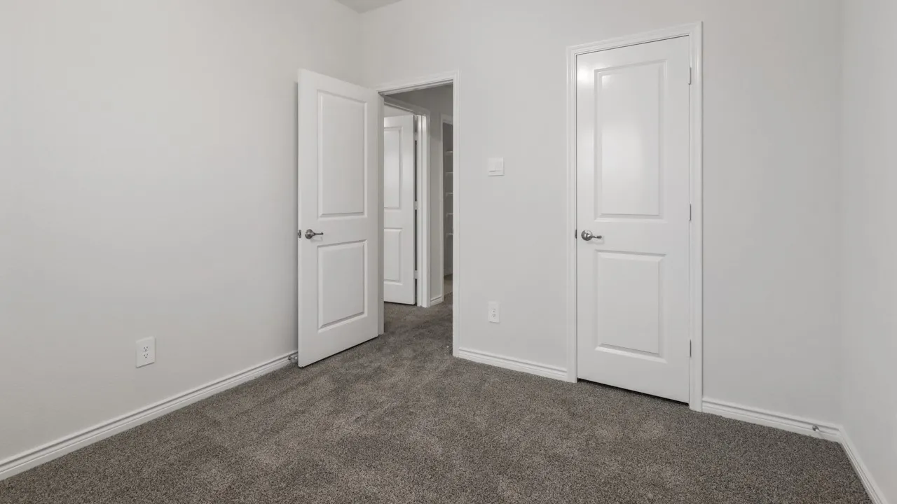 Spacious bedroom featuring neutral wall finishes, dark gray carpeting, and multiple white six-panel doors with polished chrome hardware