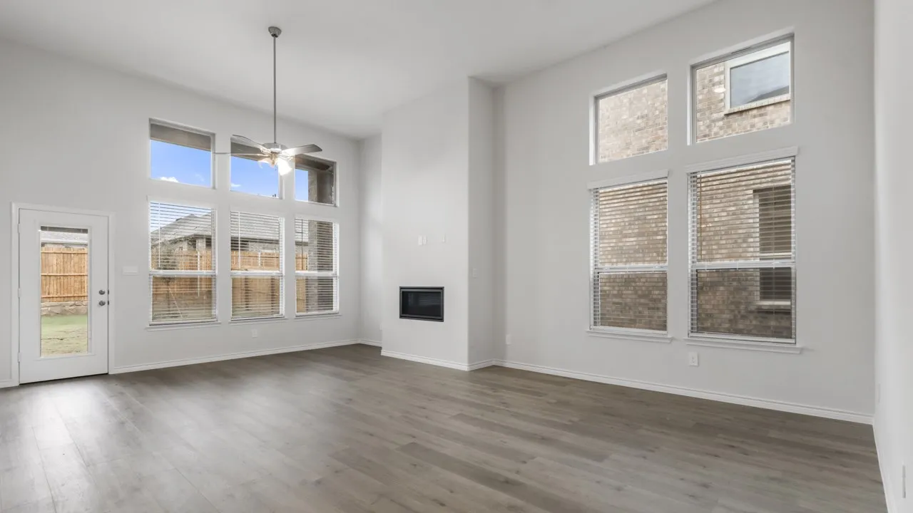Expansive living area featuring soaring ceilings, a modern electric fireplace, wood-finish flooring, and multiple large windows with blinds