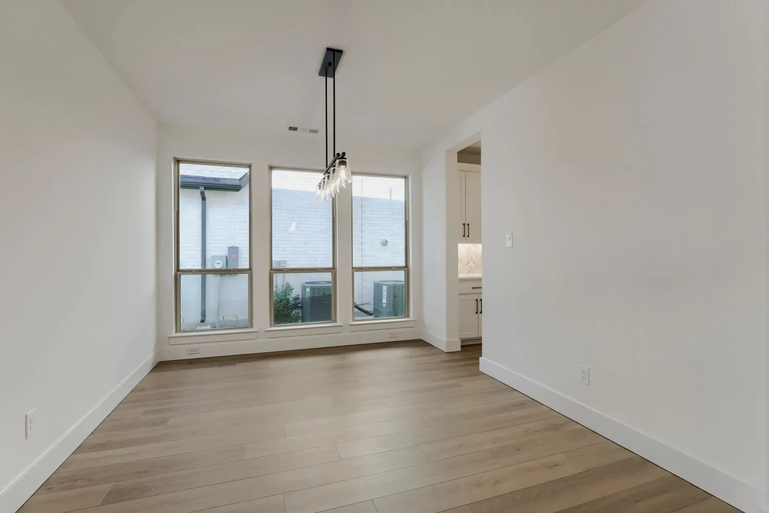 Wood-finish flooring, multiple large windows, and a linear black chandelier