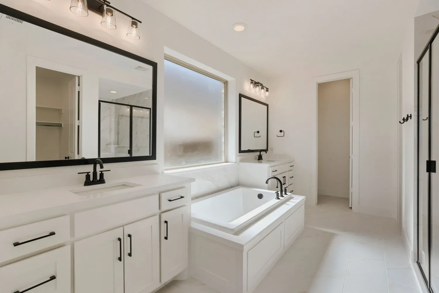 Dual vanities with white cabinetry, integrated sinks, and matte black hardware