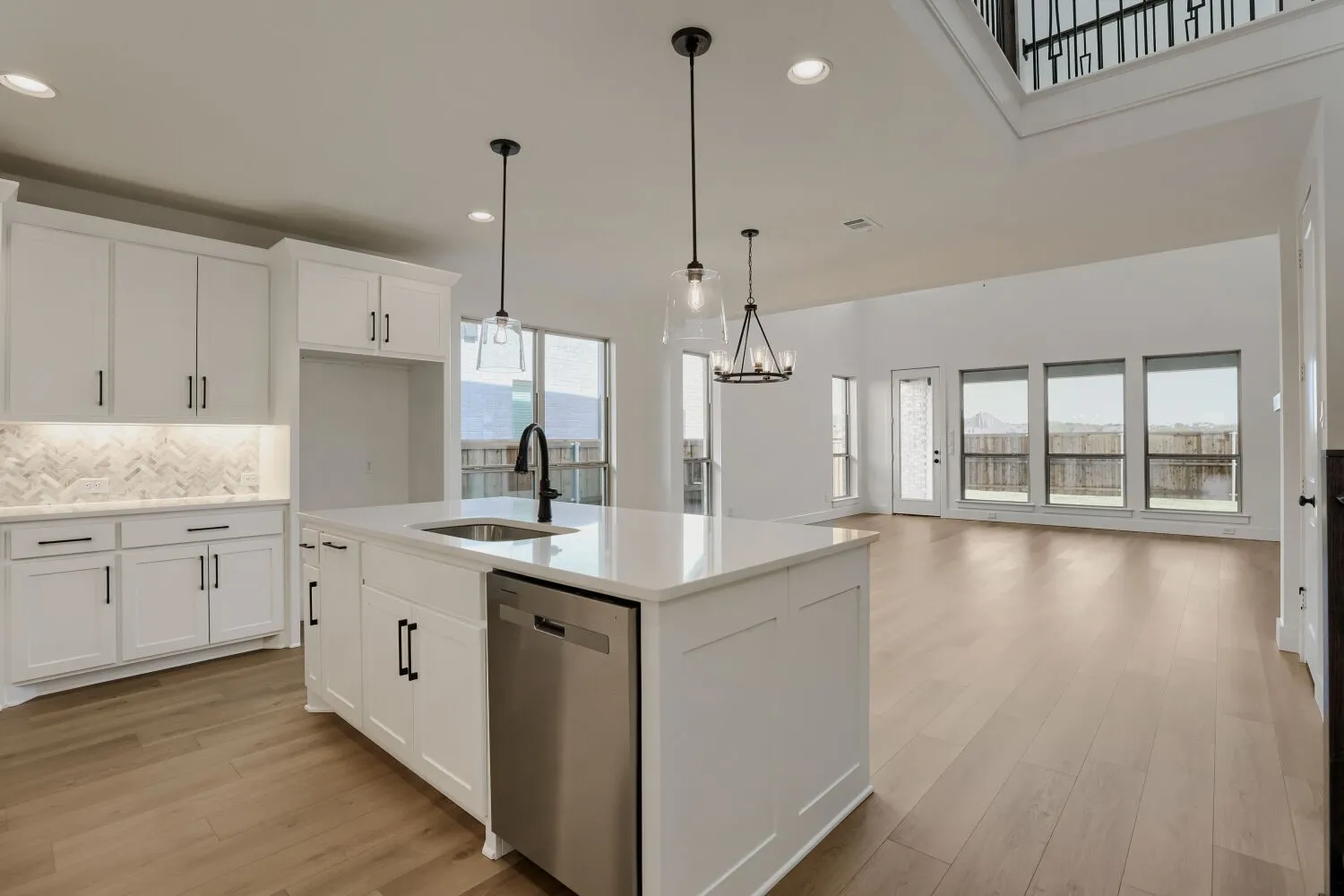 Open-concept kitchen with a central island, white cabinetry, undermount sink, and stainless steel dishwasher