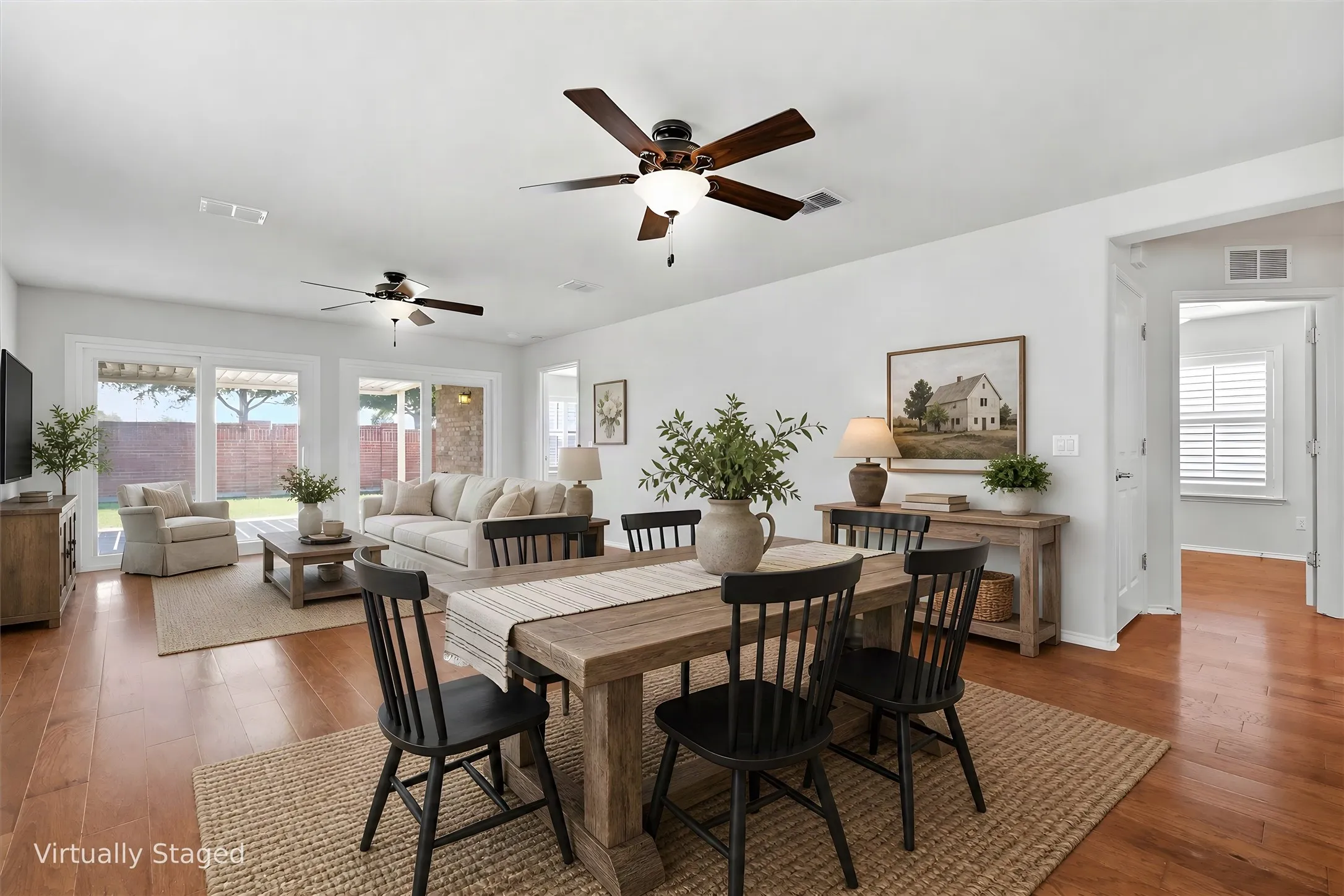 Open-concept living and dining area featuring wood-finish flooring, ceiling fans with integrated lighting, and abundant natural light from large multi-pane windows