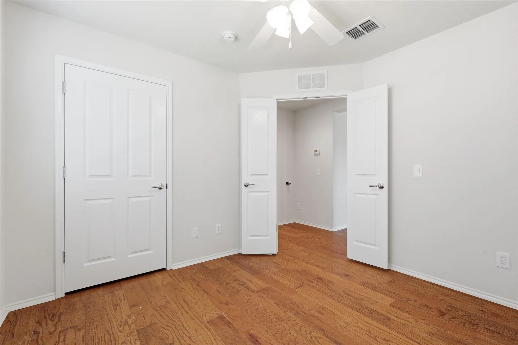 Bright interior space featuring wood-finish flooring, white trim, and a ceiling fan