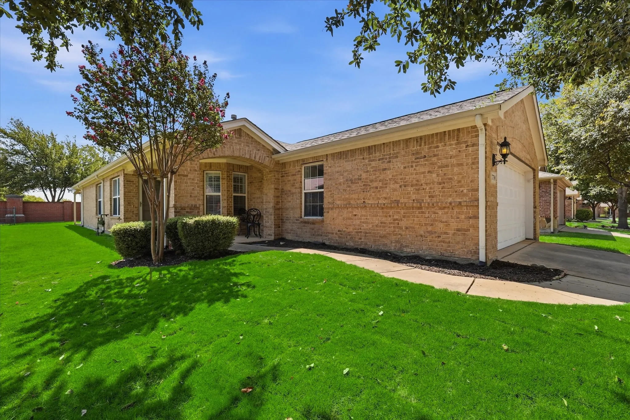 Charming brick ranch home featuring a manicured front lawn with mature landscaping, gabled roofline with architectural detailing